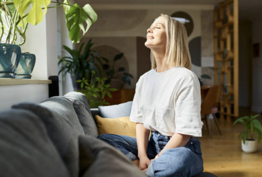 Woman sitting peacefully in plant-filled home